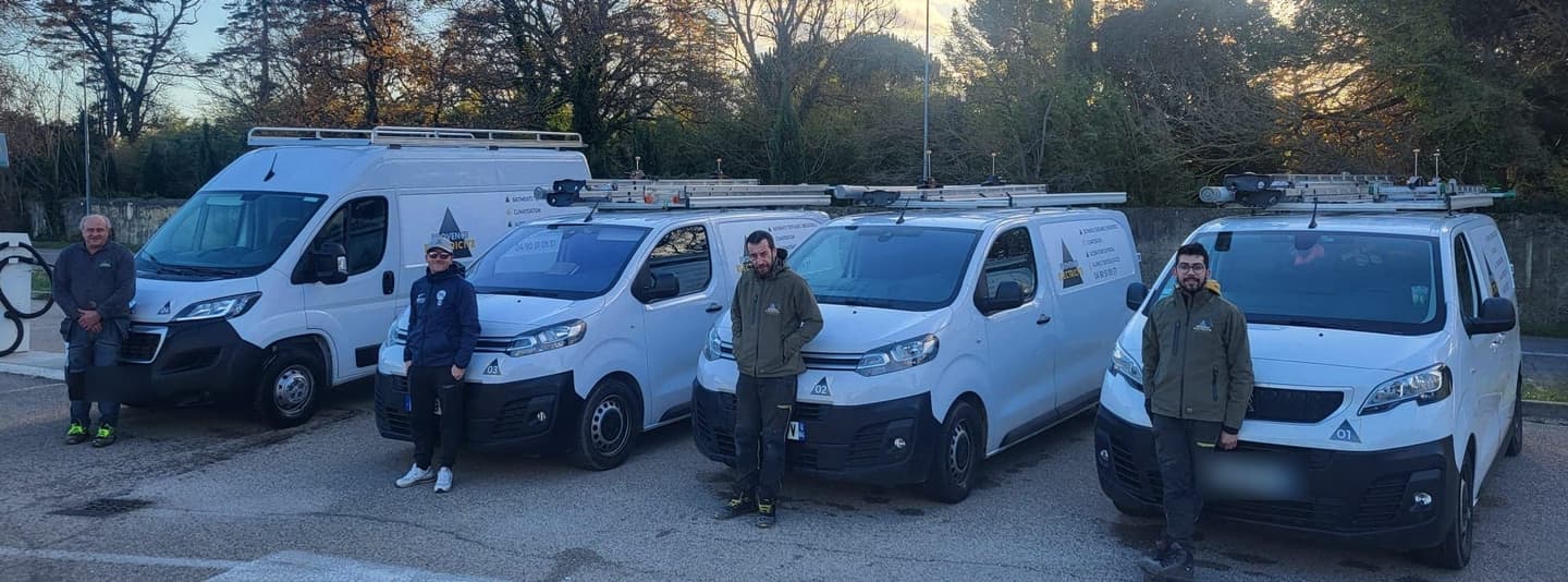 Quatre fourgons de l'entreprise alignés, l'équipe devant