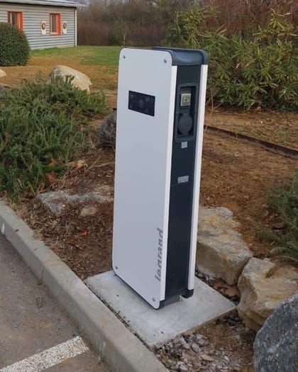 Borne de recharge sur pied installée sur un socle béton en extérieur