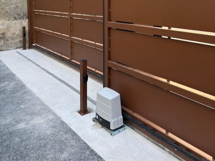 Portail coulissant motorisé installé le long d'un mur en pierre sèche